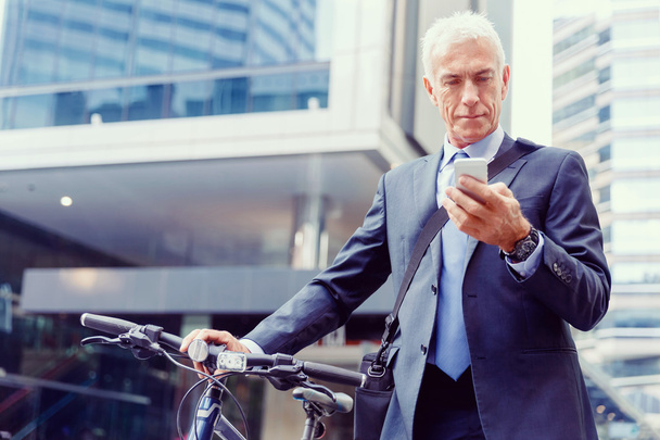 Successful businessman on bicycle with mobile phone - Fotografie, Obrázek