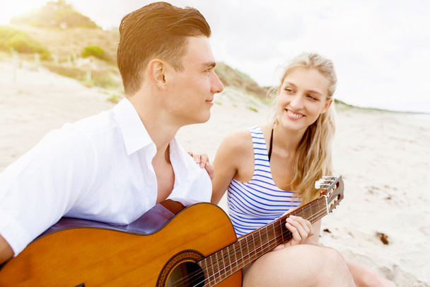 Fiatal pár gitározni szerelmes a tengerparton - Fotó, kép