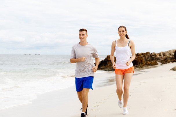 Runners. Young couple running on beach - Photo, image