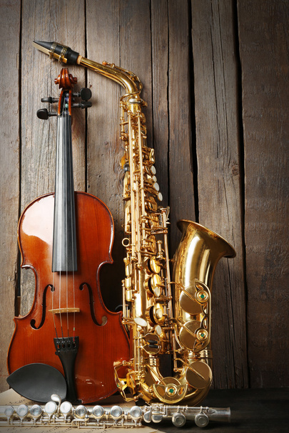 Musical instruments: saxophone, violin and flute with notes on wooden background - Valokuva, kuva