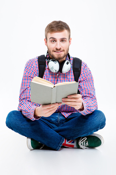 Attractive bearded student with headphones sitting and reading book - Фото, зображення
