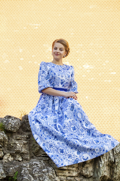 Beautiful blonde girl in blue dress posing against a background  - Valokuva, kuva