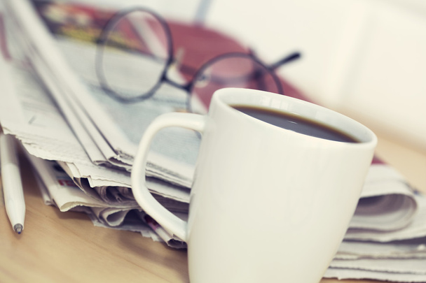 Cup of coffee and newspaper on table - Фото, изображение