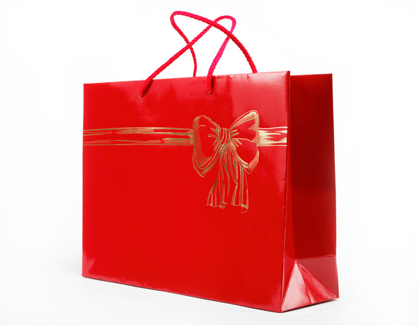 Red gift bag in the women's hands on a white background. - Foto, afbeelding