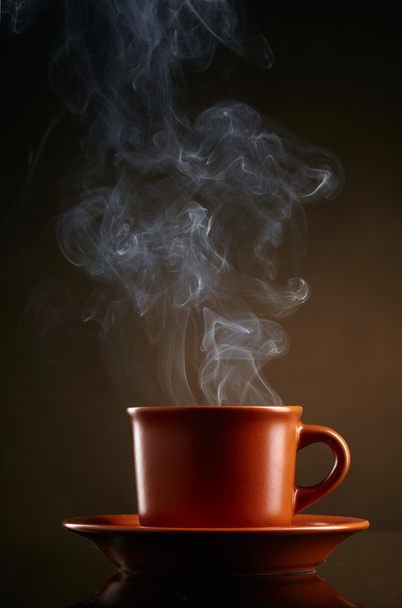 Cup of coffee with smoke over dark background - Foto, Bild