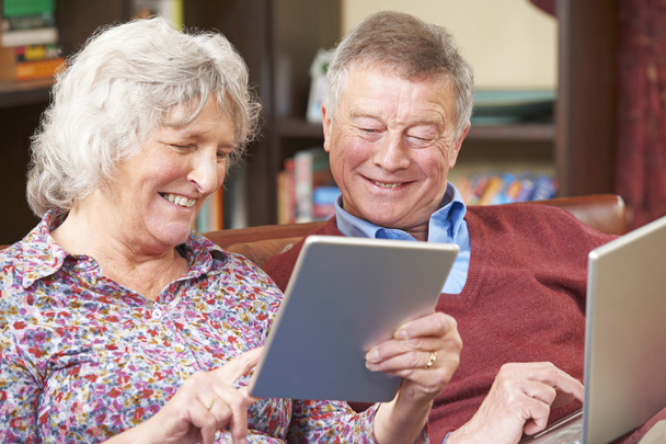 Coppia anziana che utilizza tablet e laptop digitali a casa
 - Foto, immagini