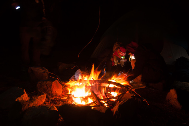 Caminhantes reunidos em torno de uma fogueira à noite com longa exposição tiro
 - Foto, Imagem