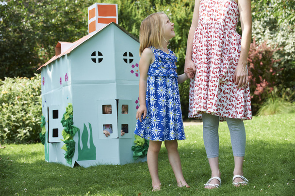 Moeder en kinderen spelen met huis gemaakte kartonnen huis - Foto, afbeelding