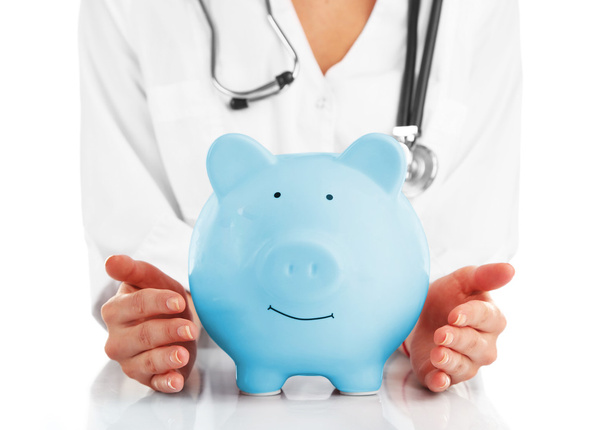 Doctor holding blue piggy bank - Фото, изображение
