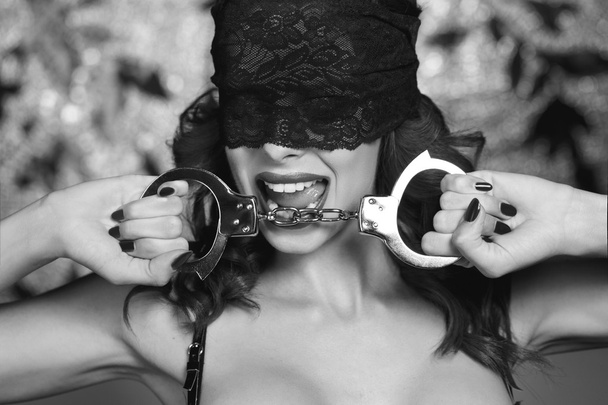 Sexy dominatrix holding handcuffs black and white - Photo, Image