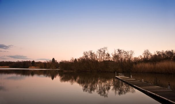 Hermoso paisaje al atardecer sobre embarcadero en el lago
 - Foto, imagen