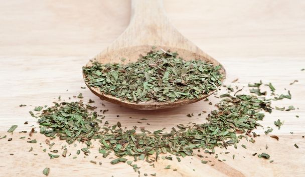 Chopped tarragon on wooden serving spoon with selective focus - Foto, afbeelding