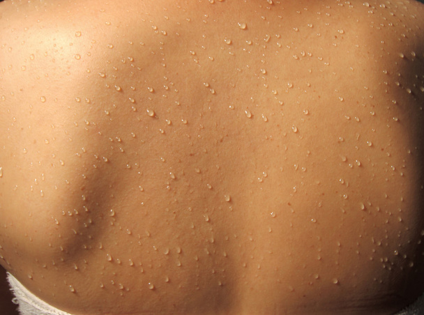 Visão de perto da parte traseira de uma mulher com gotas de água correndo pela pele molhada
 - Foto, Imagem