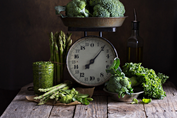 Fresh green vegetables on old kitchen scales - Foto, afbeelding