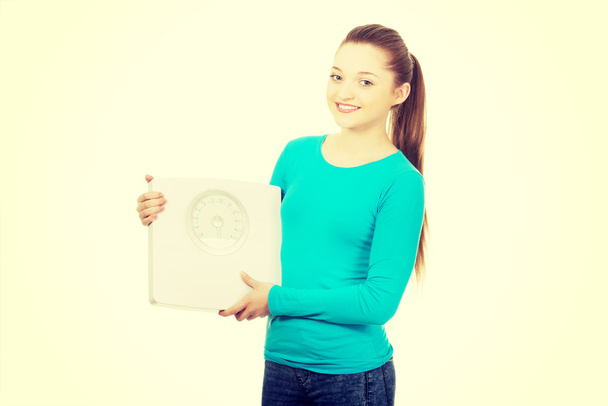 Beautiful teenager holding a scale. - 写真・画像
