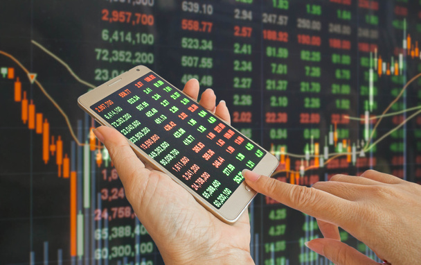 携帯電話を用いた株価の背景の手 - 写真・画像