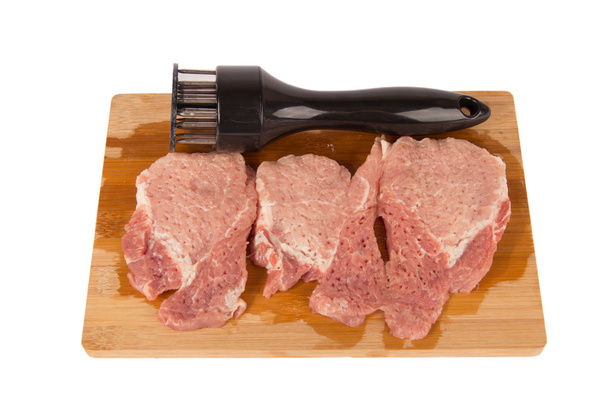 versloeg het vlees op een houten plank op een witte achtergrond - Foto, afbeelding