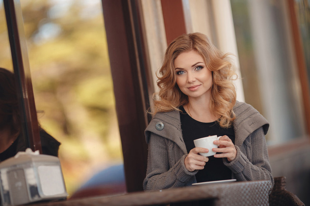 Woman drinking coffee at a table in a cafe - Foto, immagini