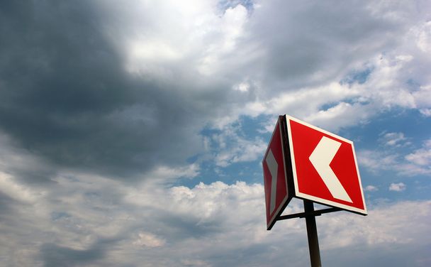 Red and white warning arrow on cloudy sky background - Photo, Image