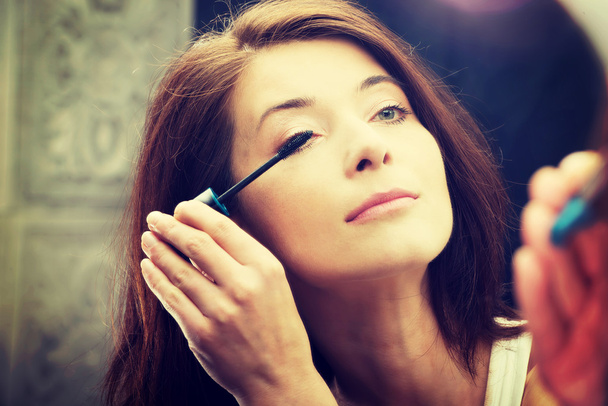 Woman makes light day makeup in bathroom. - Фото, изображение