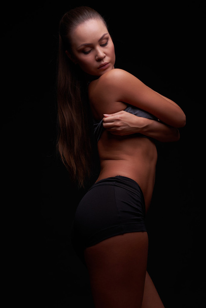 Young girl on a dark background is engaged in fitness - Fotografie, Obrázek