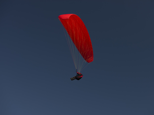 rode paraglider op heldere blauwe hemel - Foto, afbeelding