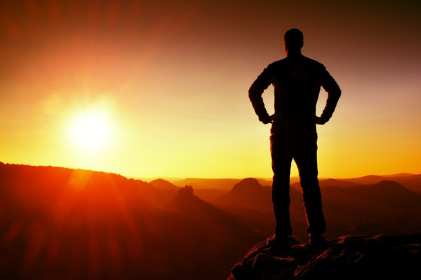 Silhouette eines jungen selbstbewussten und kraftvollen Mannes, der mit den Händen auf den Hüften steht, Morgen- oder Spätsonne mit Kopierraum - Foto, Bild