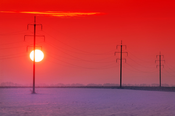 Sonnenuntergang auf dem Hintergrund von Strommasten  - Foto, Bild