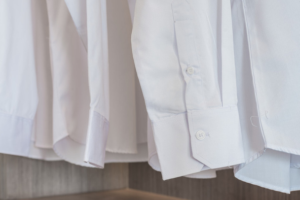 camisas colgando en rack con botones blancos
 - Foto, imagen