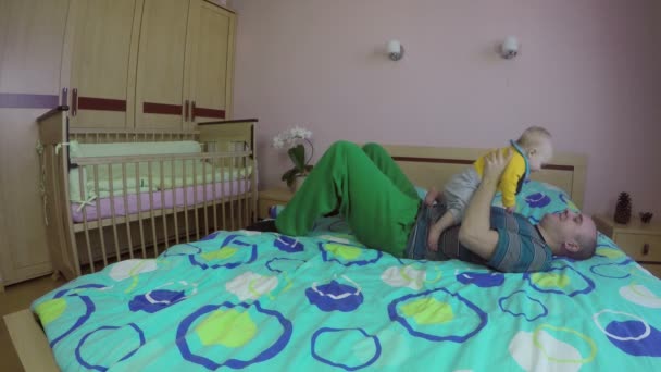 Der verspielte Familienvater hebt das kleine Mädchen auf das Bett. 4k - Filmmaterial, Video