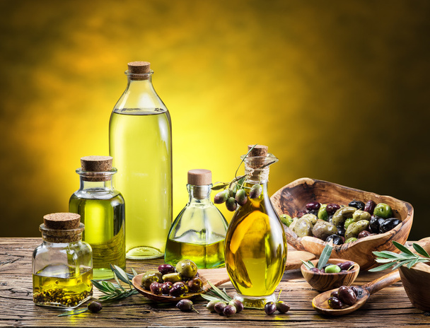 Glass bottles of olive oil and few berries on the wooden table.  - Фото, изображение