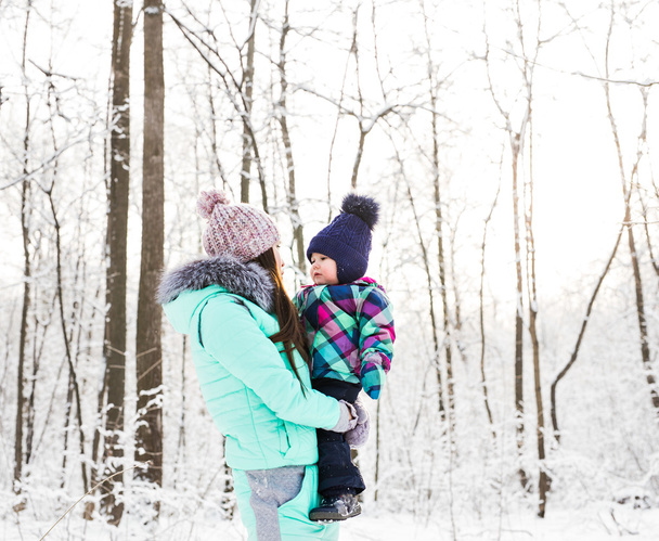 счастливая семейная мать с маленькой дочкой на зимней прогулке по лесу
 - Фото, изображение