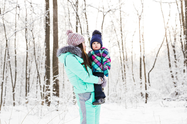 ευτυχισμένη οικογένεια μητέρα και κόρη μωρό παιδί για ένα χειμώνα με τα πόδια μέσα στο δάσος - Φωτογραφία, εικόνα