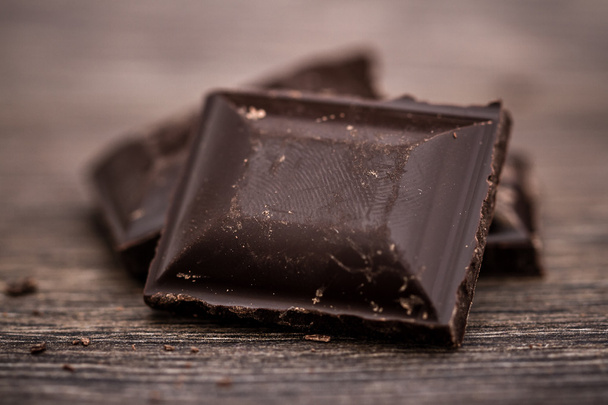 gehackte dunkle Schokoladentafeln auf Holztisch - Foto, Bild