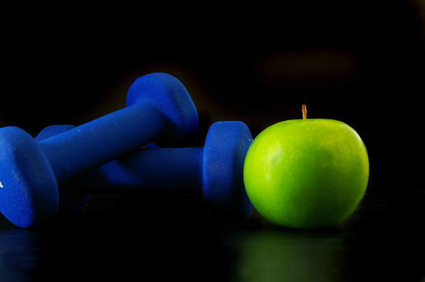 Apple and two hand weights - Photo, Image