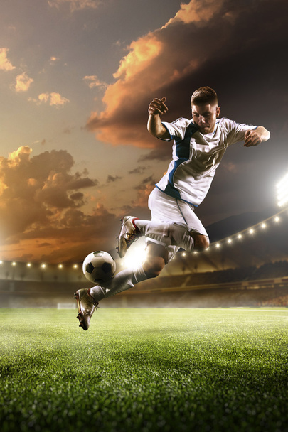 Soccer player in action on sunset stadium background - Foto, afbeelding