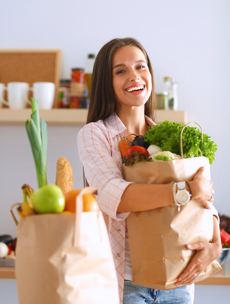 Nuori nainen tilalla ruokakauppa laukku vihanneksia - Valokuva, kuva