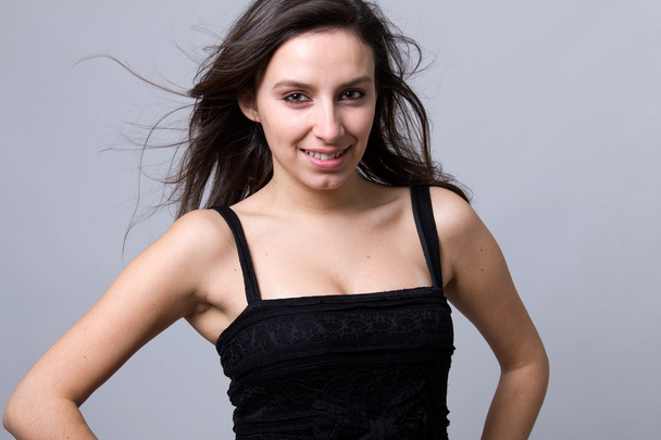 Beautiful young woman smiling, against a grey background - Φωτογραφία, εικόνα