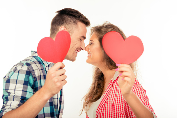Happy couple in love holding two paper hearts kissing each other - Photo, Image