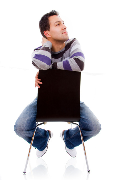 Pensive young casual man on a chair, isolated on white - 写真・画像