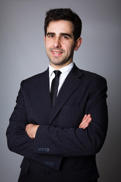 Handsome young business man standing on grey background - Fotó, kép