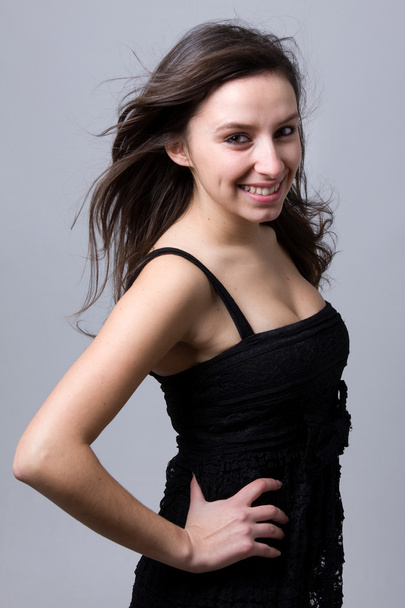 Beautiful young woman smiling, against a grey background - Foto, imagen
