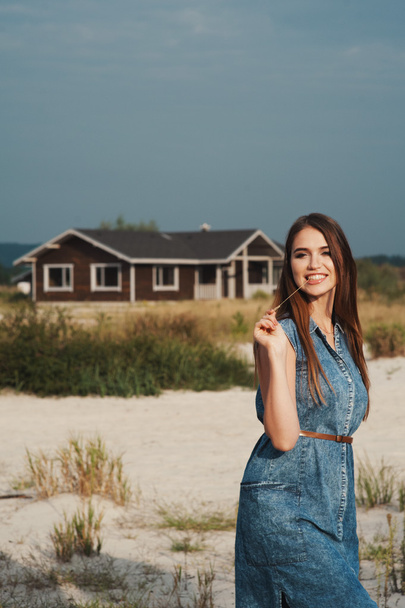 brown haired rural lady standing on sand against ranch house - Foto, Imagem