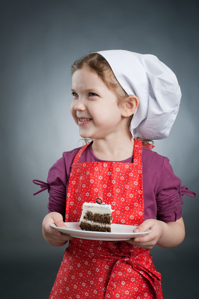 A girl in a white hat with a cake on a plate - Foto, afbeelding
