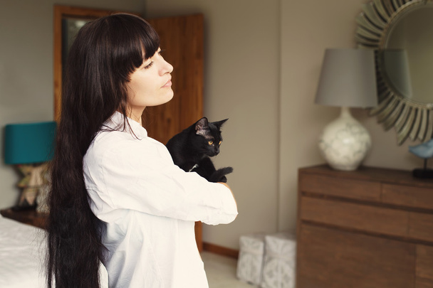 Girl with black hair style holding black cat in hands - Zdjęcie, obraz