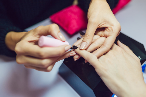 Manicure. Beauty saloon. Close-up. Apply black nail polish. - Foto, Bild