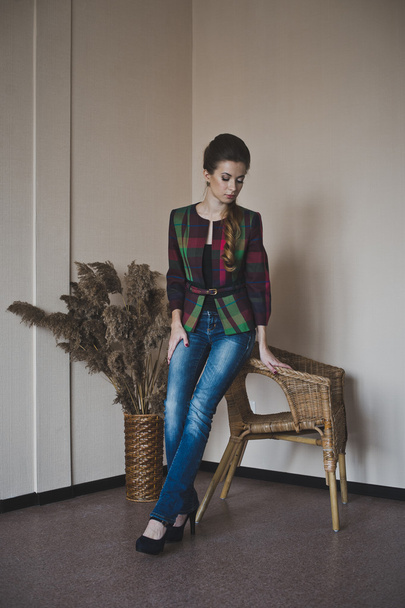 A beautiful girl stands near the chairs and the vase with reeds  - Fotografie, Obrázek
