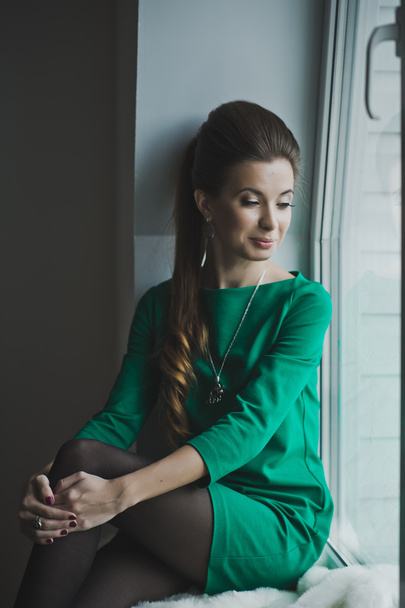 Portrait of a girl with a long braid at the window 4899. - Foto, Bild