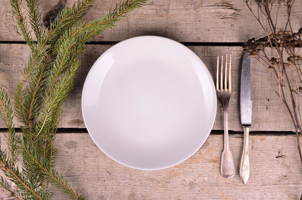 Порожня тарілка, посуд та ялинка. Вид зверху над білим дерев'яним фоном столу
 - Фото, зображення