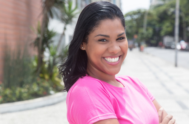 Portrait of a native latin woman in a pink shirt in city - 写真・画像